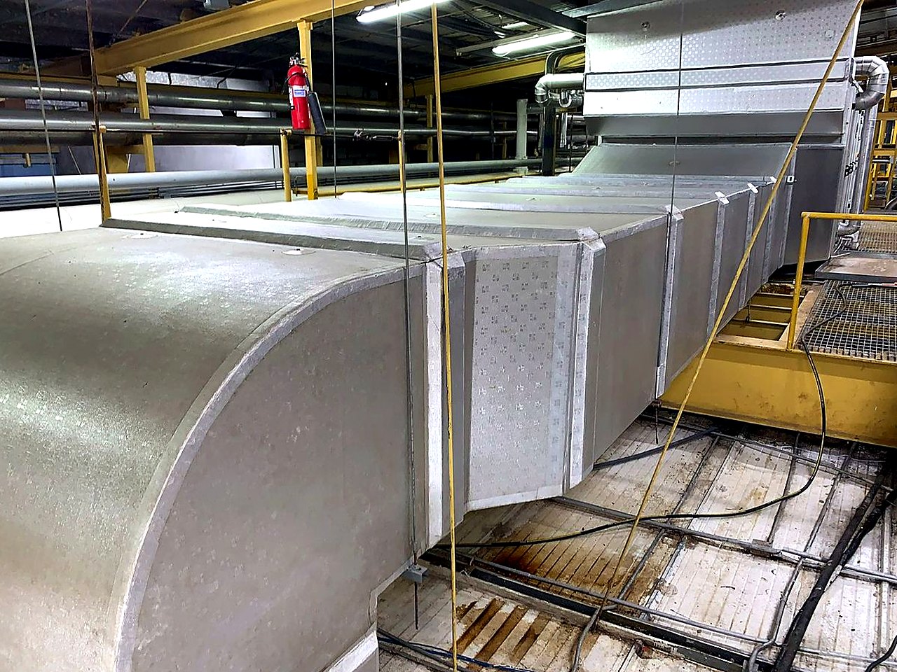 Ductería aislada de gran sección recorriendo el techo de una planta industrial