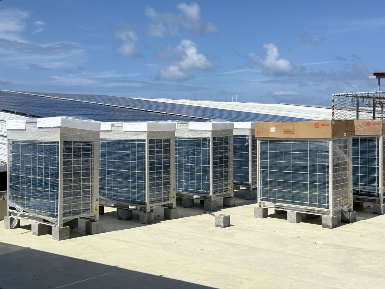 Las unidades Trane TVR PRO en la azotea el día de la entrega, todavía embaladas. Al fondo, el campo de paneles solares del edificio.
