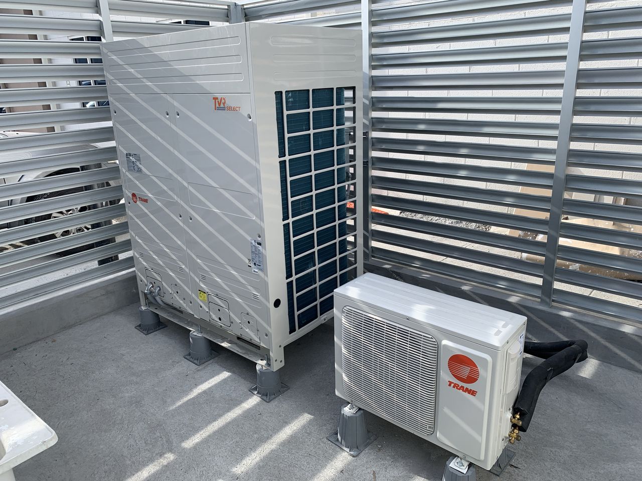 La unidad exterior Trane TVR Select y un split, sobre soportes antivibración dentro de la celosía.